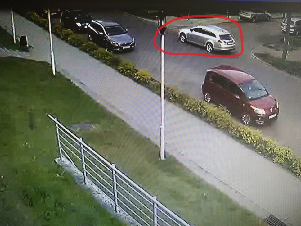 Zdjęcie kolorowe: obraz z monitoringu: ulica z zaparkowanymi samochodami i mężczyzna, który kierował srebrnym samochodem osobowym