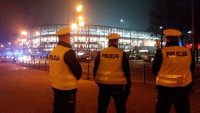 3 policjantów ruchu drogowego stojących w rejonie skrzyżowania przed oświetlonym stadionem piłkarski w Zabrzu