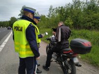 Zdjęcie kolorowe: umundurowani policjanci zabrzańskiej drogówki podczas kontroli drogowej motocyklisty na DK 88