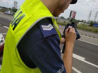 Zdjęcie kolorowe: policjant drogówki z urządzeniem do pomiaru prędkości pojazdów