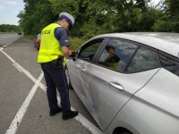 Zdjęcie kolorowe: policjant drogówki podczas kontroli pojazdu