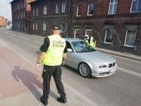 Zdjęcie kolorowe: policjant ruchu drogowego  i funkcjonariusz z Krajowej Administracji Skarbowej zatrzymują pojazd do kontroli