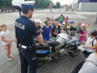 zdjęcie kolorowe: Policjant pod stadionem miejski w Zabrzu pokazuje dzieciom motocykl służbowy