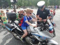 zdjęcie kolorowe: Policjant pod stadionem miejski w Zabrzu pokazuje dzieciom motocykl służbowy