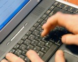 Zdjęcie kolorowe: dłonie osoby dorosłej piszące na czarnej klawiaturze komputerowej
