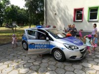 Zdjęcie kolorowe: Radiowóz policyjny i grupa dzieci