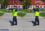 Zdjęcie kolorowe: umumdurowana policjantka wydziału ruchu drogowego użozliwia pojazdom nadjeżdzającym z lewej strony wykonanie bezpiecznego manewru skretu w lewo