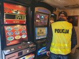 zdjęcie kolorowe: policjant w lokalu w którym zabezpieczono nielegalne automaty, na  tle automatów do gier hazardowych