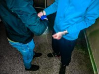Zdjęcie kolorowe: policjanci KMP Zabrze prowadzą zatrzymanego mężczyznę w kajdanach zespolonych.