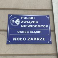 Zdjęcie kolorowe: Tabliczka z napisem &quot;Polski Związek Niewidomych, Okręg Śląski, Koło Zabrze&quot;